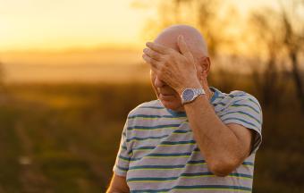 A man wiping forehead while walking in nature